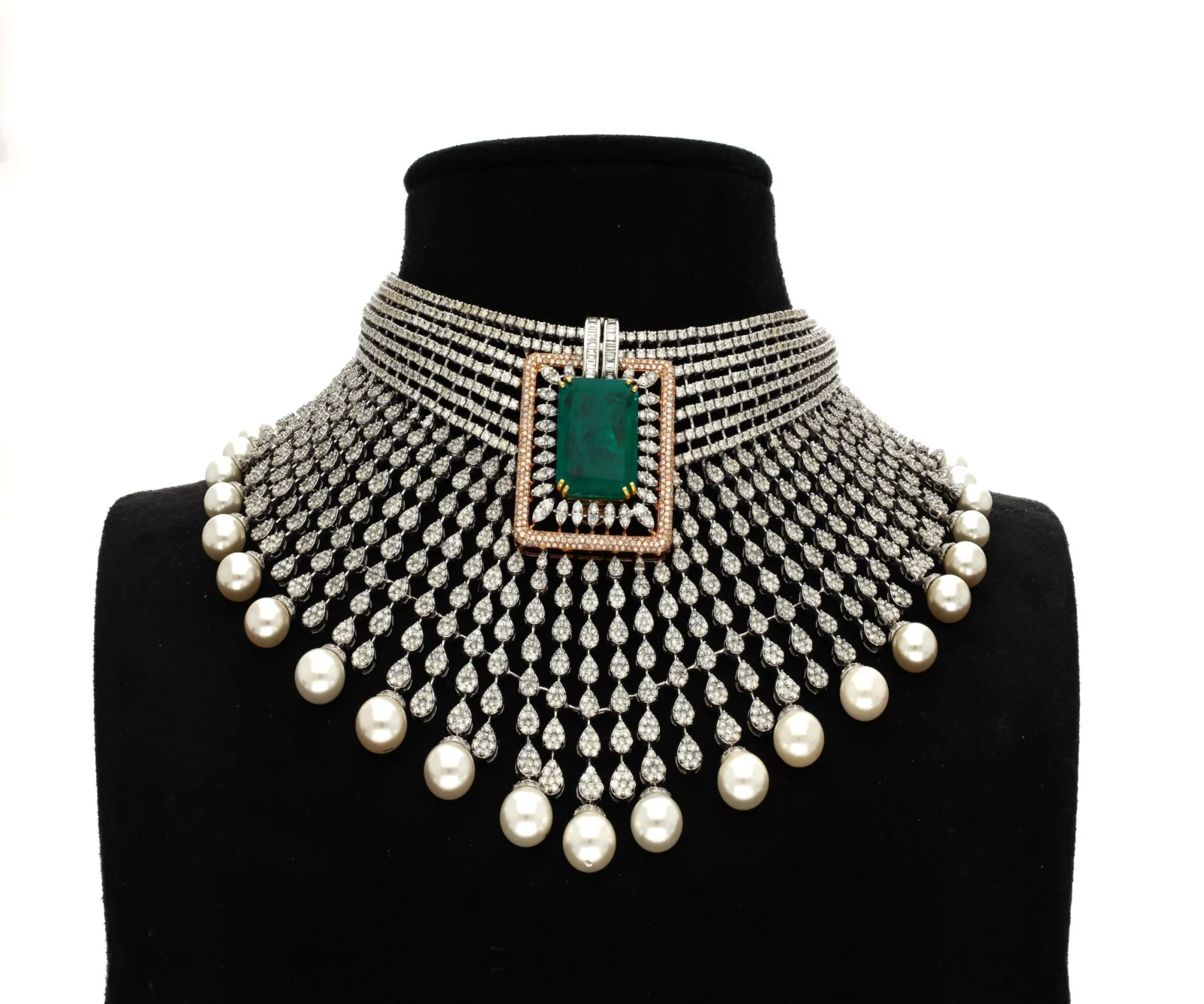 A stone-set choker with a green centre stone and pearl drops displayed on a black velvet bust