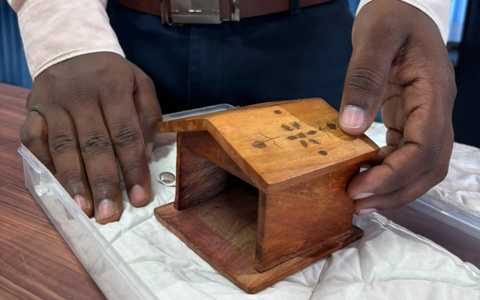 A wooden house being placed on a soft cloth in a tray, ready for product photography