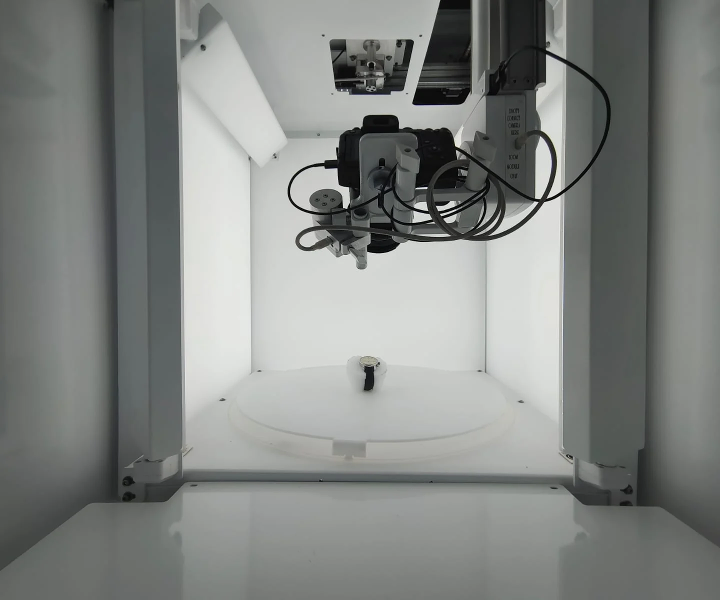 Inside an EasyCLIQ studio: lit walls, the camera on its mount and a watch on the turntable