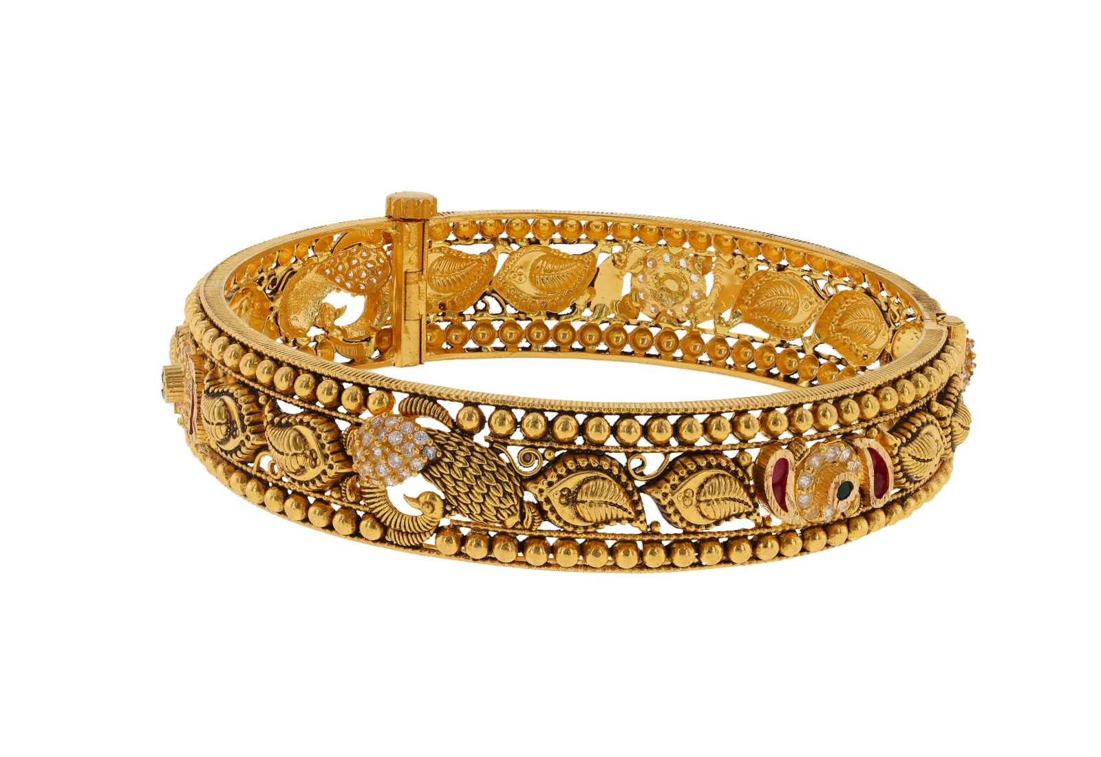 A gold bangle with beaded borders, leaf motifs and a stone-set peacock, photographed on white