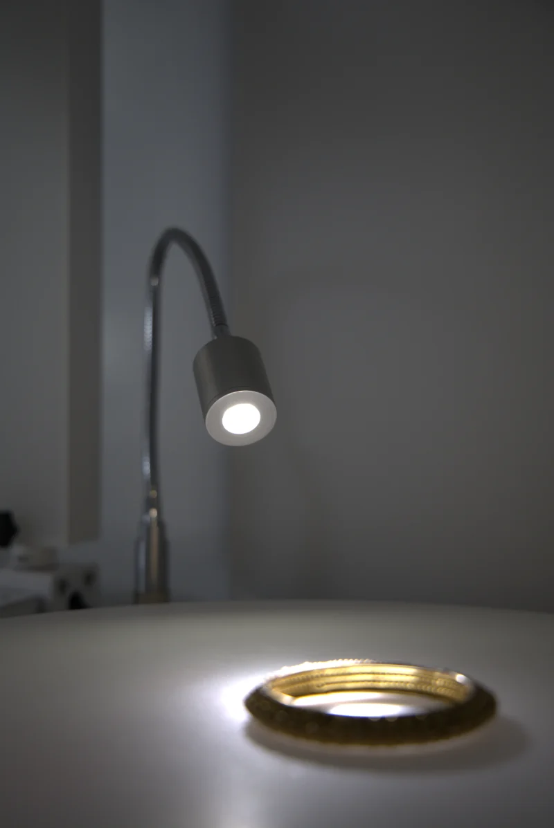 A focus light on a flexible arm lighting a gold bangle