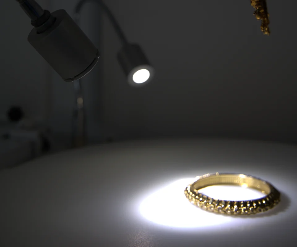 A focus light on a flexible arm lighting a gold bangle